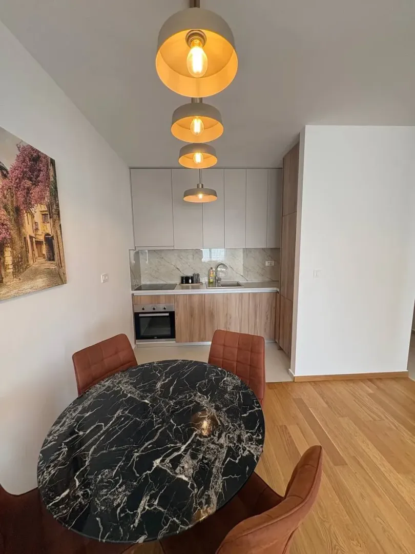 Kuhinja sa trpezarijskim dijelom i modernim lusterima.