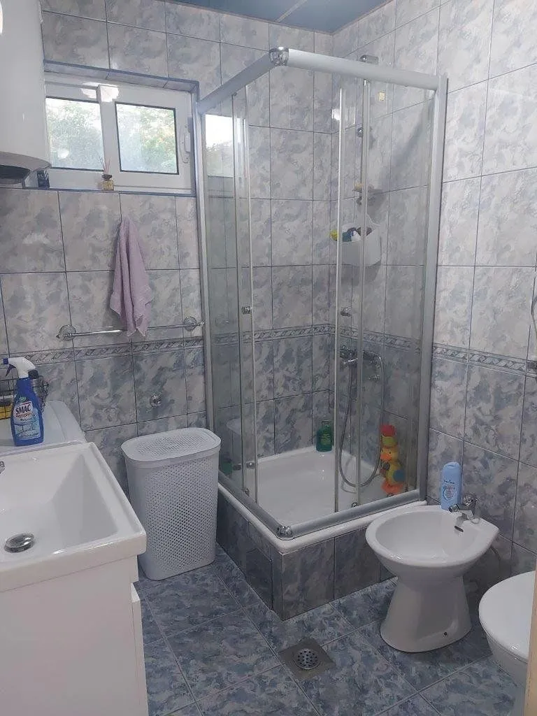 Kupatilo obloženo pločicama sa tuš kabinom, umivaonikom i sanitarijama.