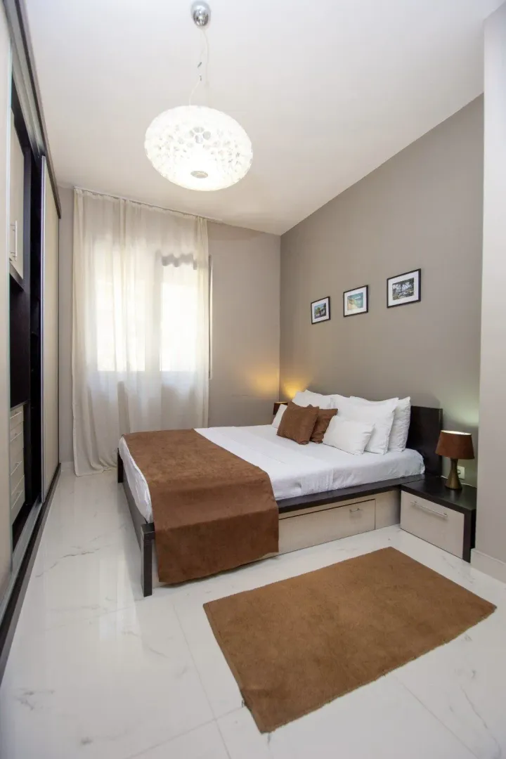 Modern bedroom with a double bed, wardrobe, and lighting.