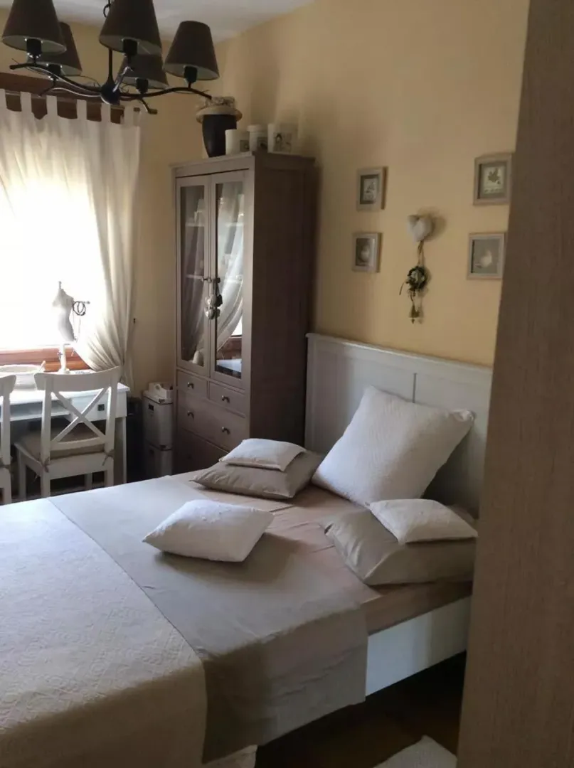 Namještena spavaća soba sa bračnim krevetom, ormarom i prozorom.