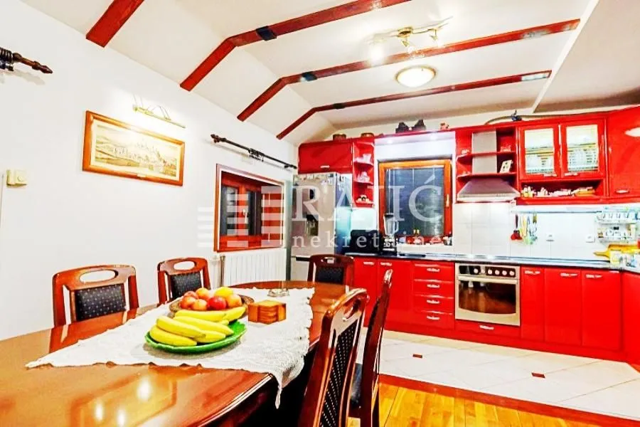 Spacious kitchen with a dining area and red kitchen elements.