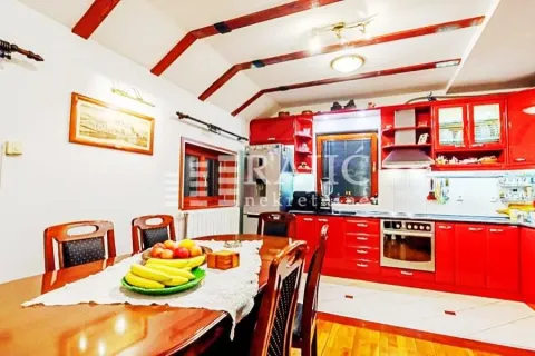 Spacious kitchen with a dining area and red kitchen elements. - image 5