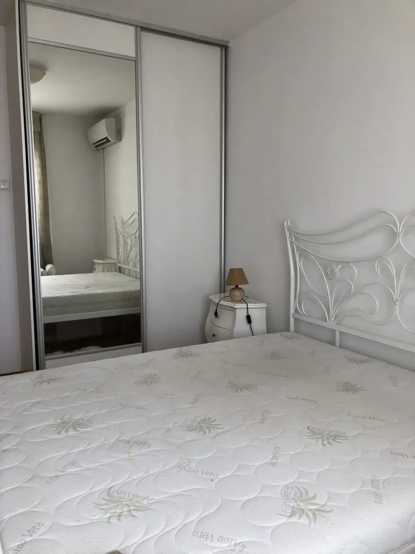 Simple bedroom with a white bed and a built-in wardrobe with a mirror.
