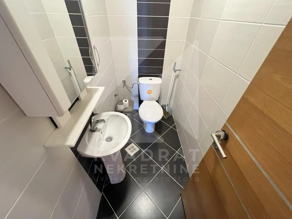 Small bathroom with washbasin, toilet bowl and tiles.