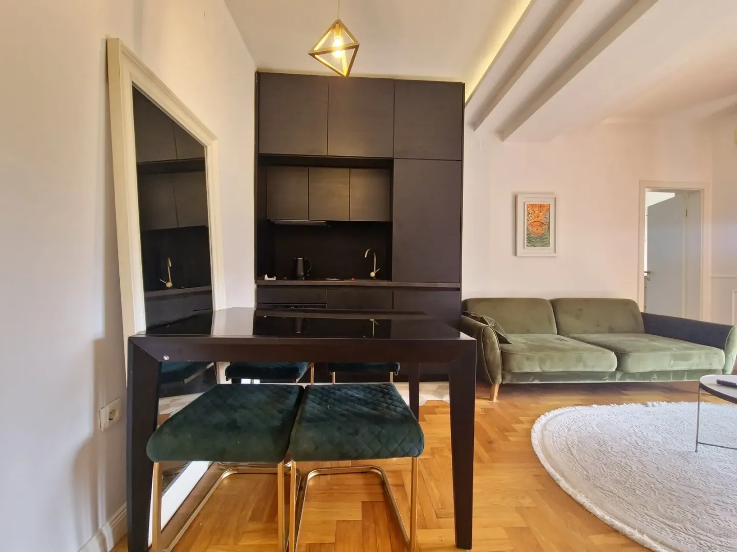 Living room with a dining area and a modern black kitchen in the background.
