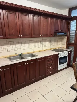 Kuhinja sa tamnim drvenim elementima, bijelom radnom pločom i keramičkim pločicama. - image 3