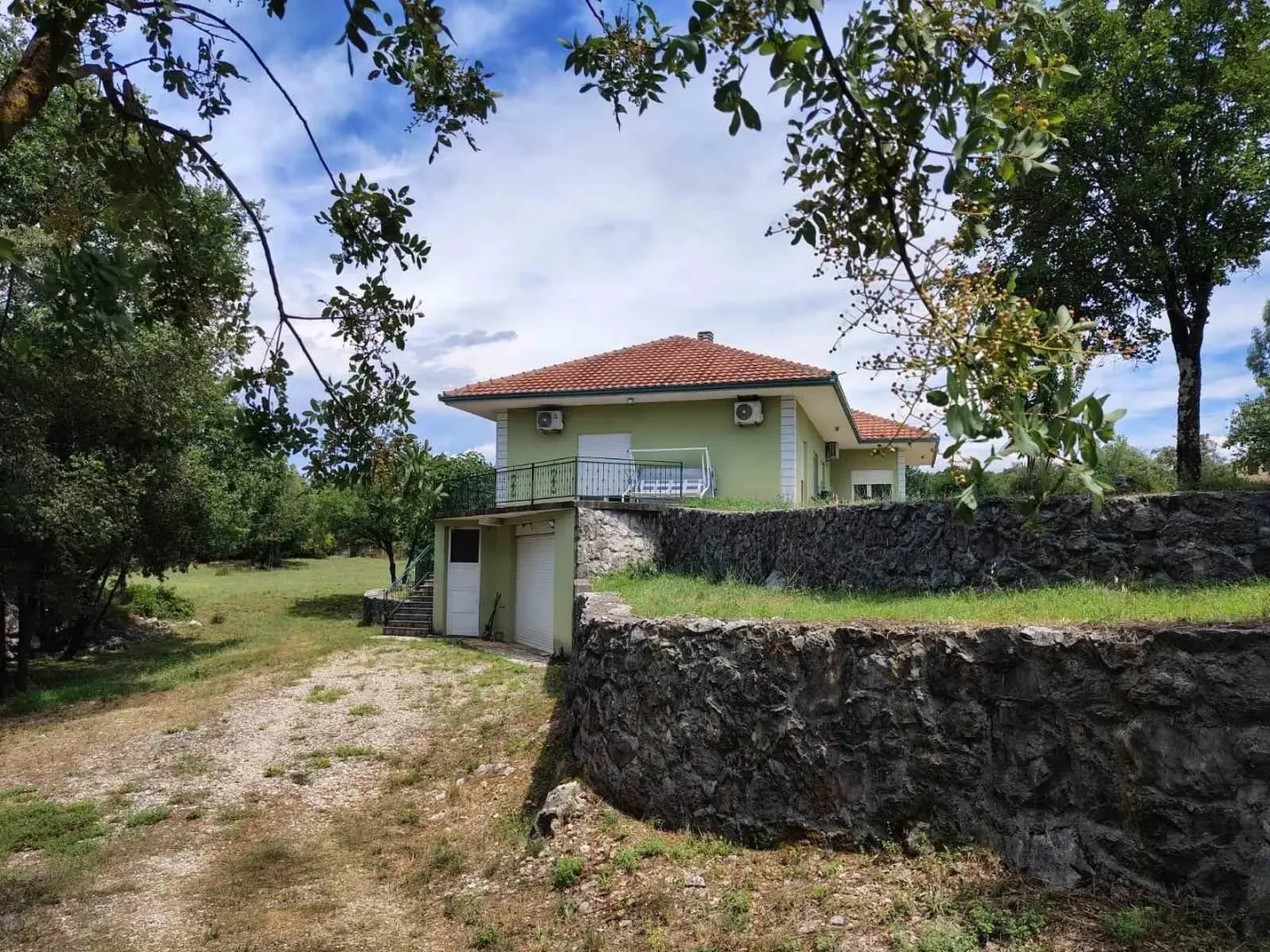View of the exterior of the house with a yard and a stone wall.