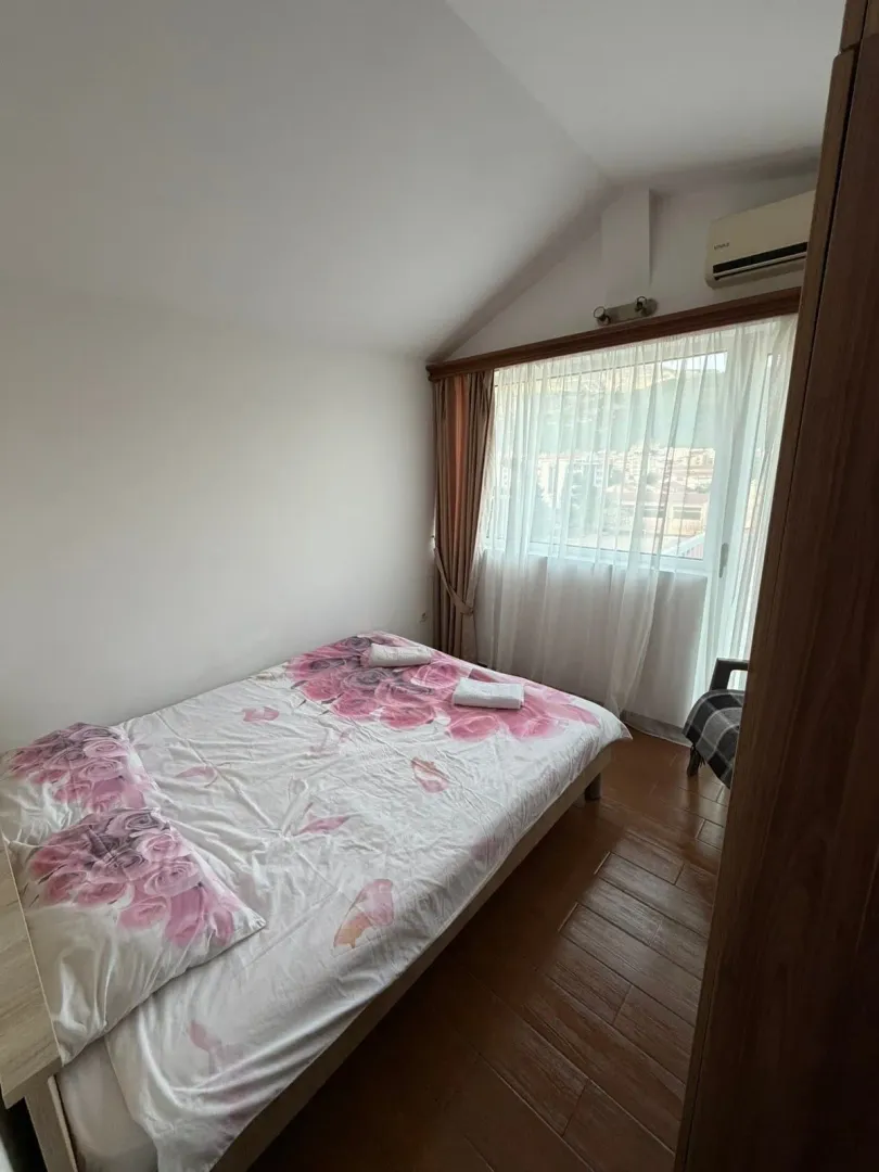 Spavaća soba sa bračnim krevetom i prozorom koji gleda spolja.