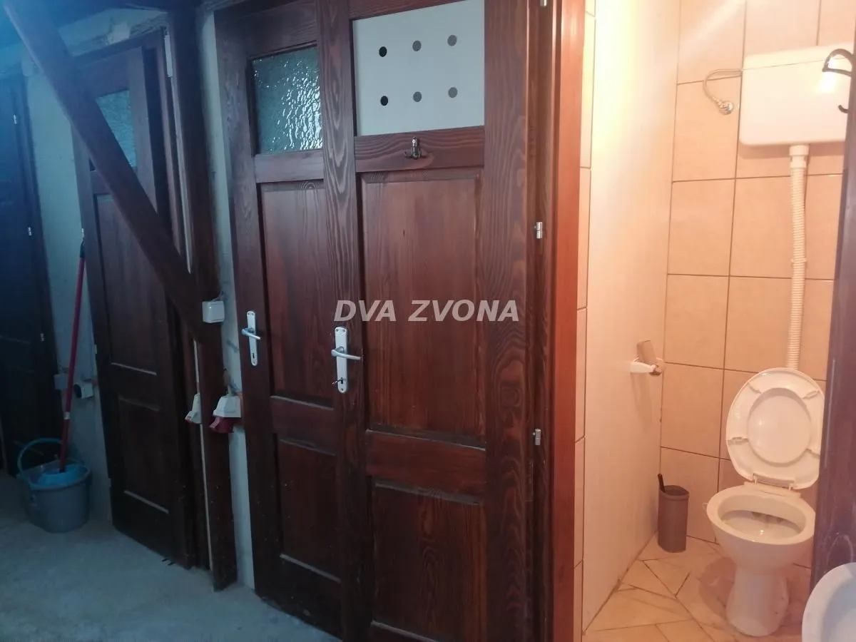 Small bathroom with a toilet next to wooden doors.
