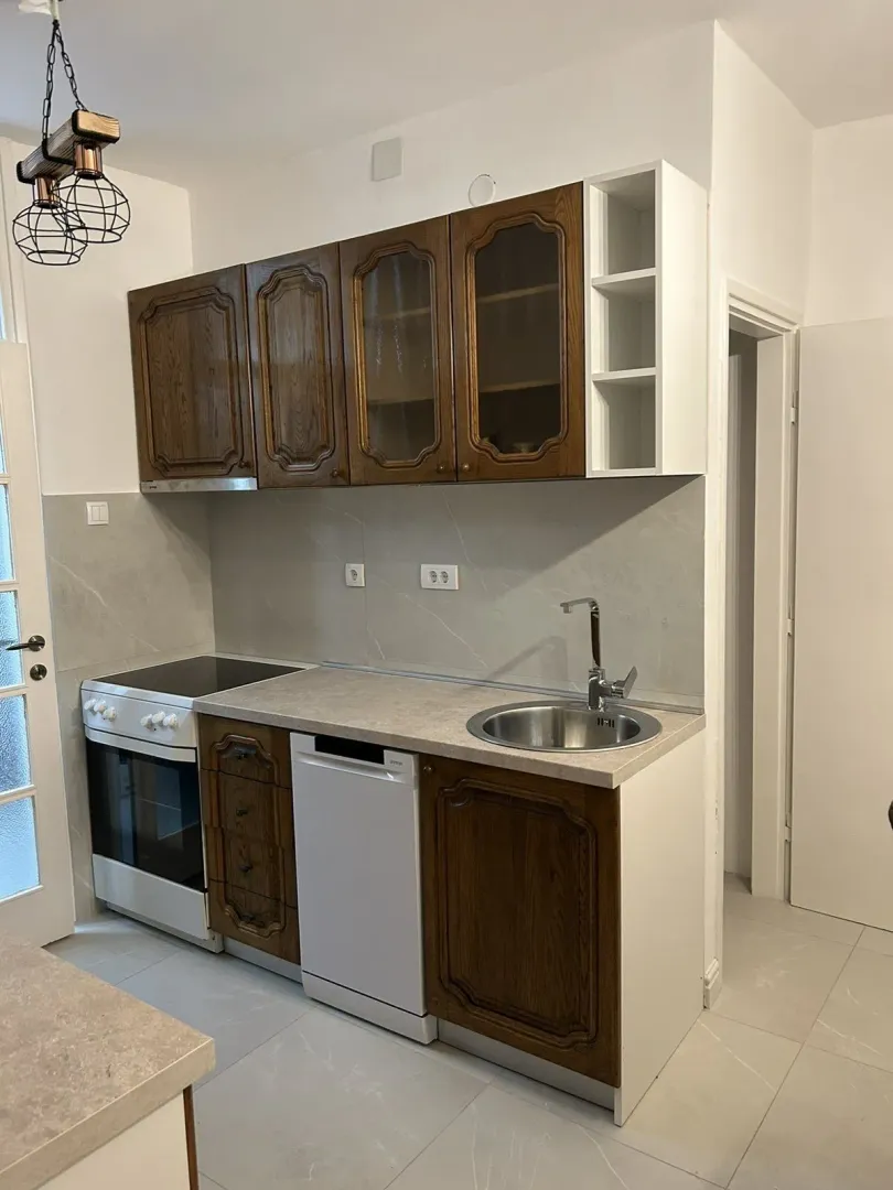 Kitchen with wooden cabinets, a sink, and a stove.
