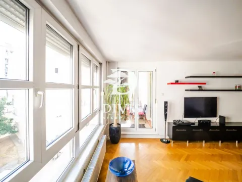 Dnevna soba sa parketom, velikim prozorima i televizorom na zidu. - image 11