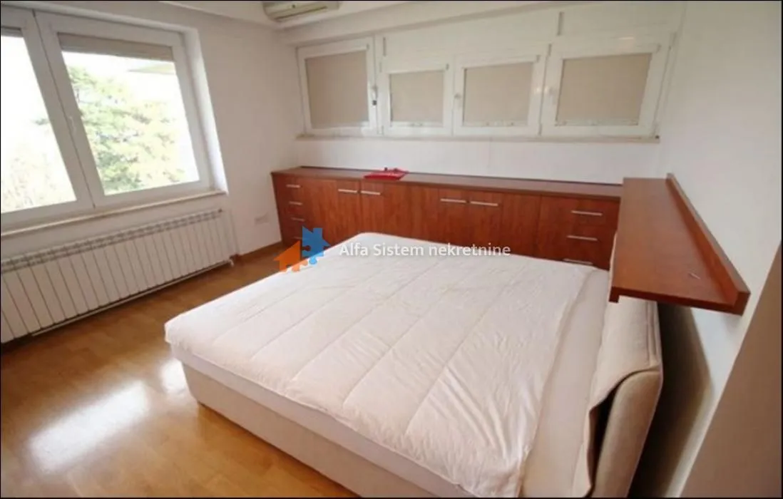 Bedroom with a double bed and built-in cabinets under the windows.