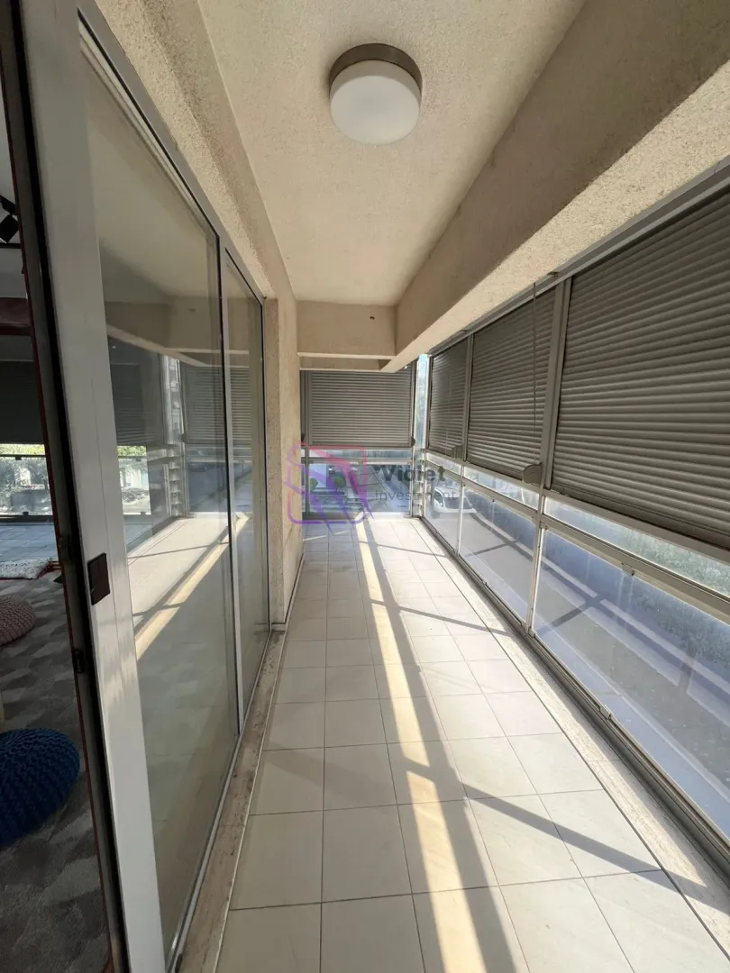 Natkriveni balkon sa popločanim podom i staklenom ogradom.