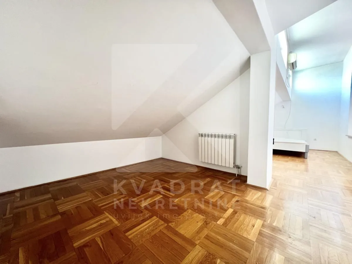 Empty attic room with parquet flooring and a sloped ceiling.