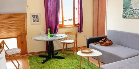 Dnevna soba sa sivom sofom, trpezarijskim stolom i ljubičastim zavesama. - image 2