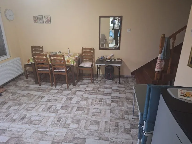 Trpezarija sa stolom, stolicama i stepeništem u uglu prostorije.