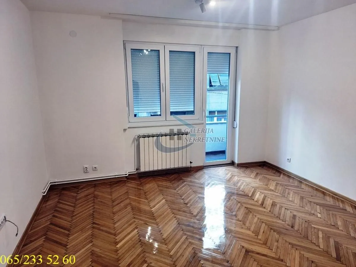 Empty room with hardwood flooring and access to a balcony.
