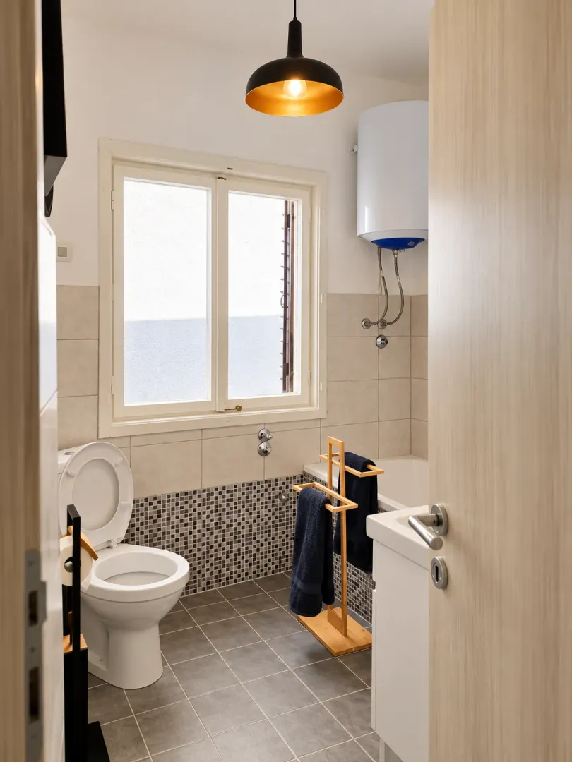 Smaller bathroom with a toilet, bathtub, and window.