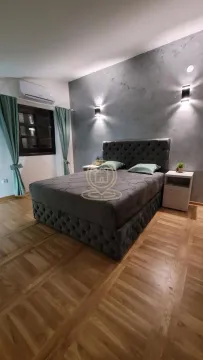 Prostrana spavaća soba sa velikim bračnim krevetom i dekorativnim osvetljenjem na zidu. - image 9
