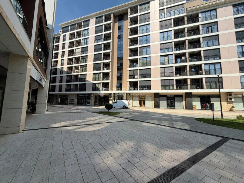 Spoljašnji izgled moderne stambene zgrade sa popločanim dvorištem.