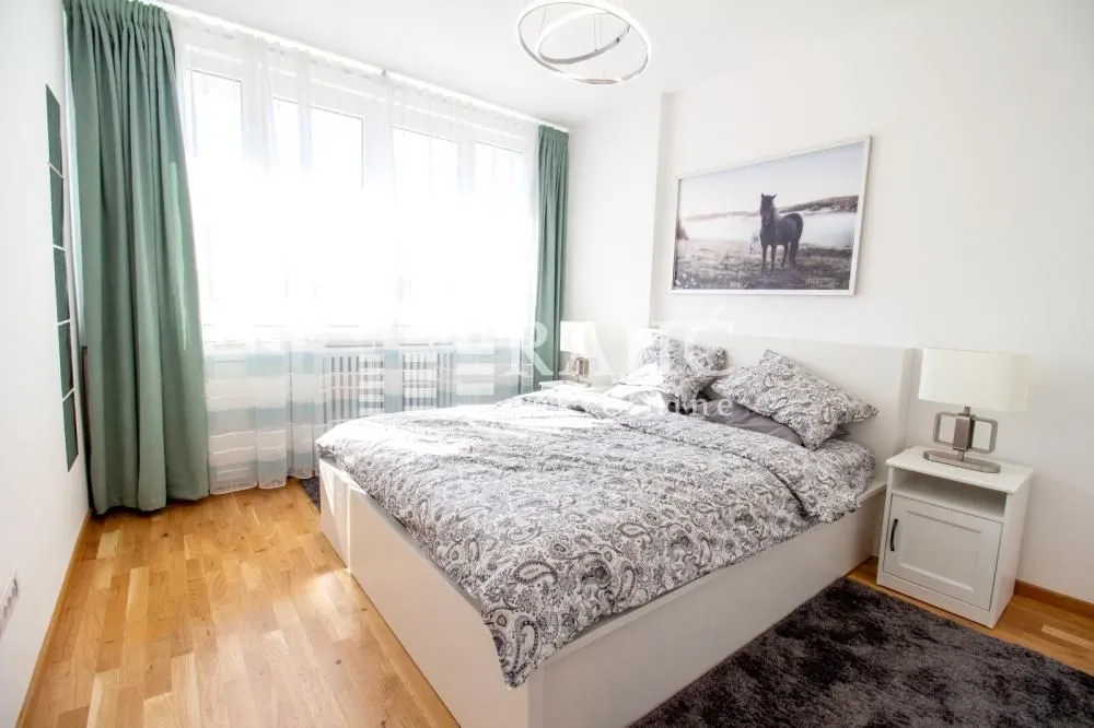 Furnished bedroom with a double bed and a large window.