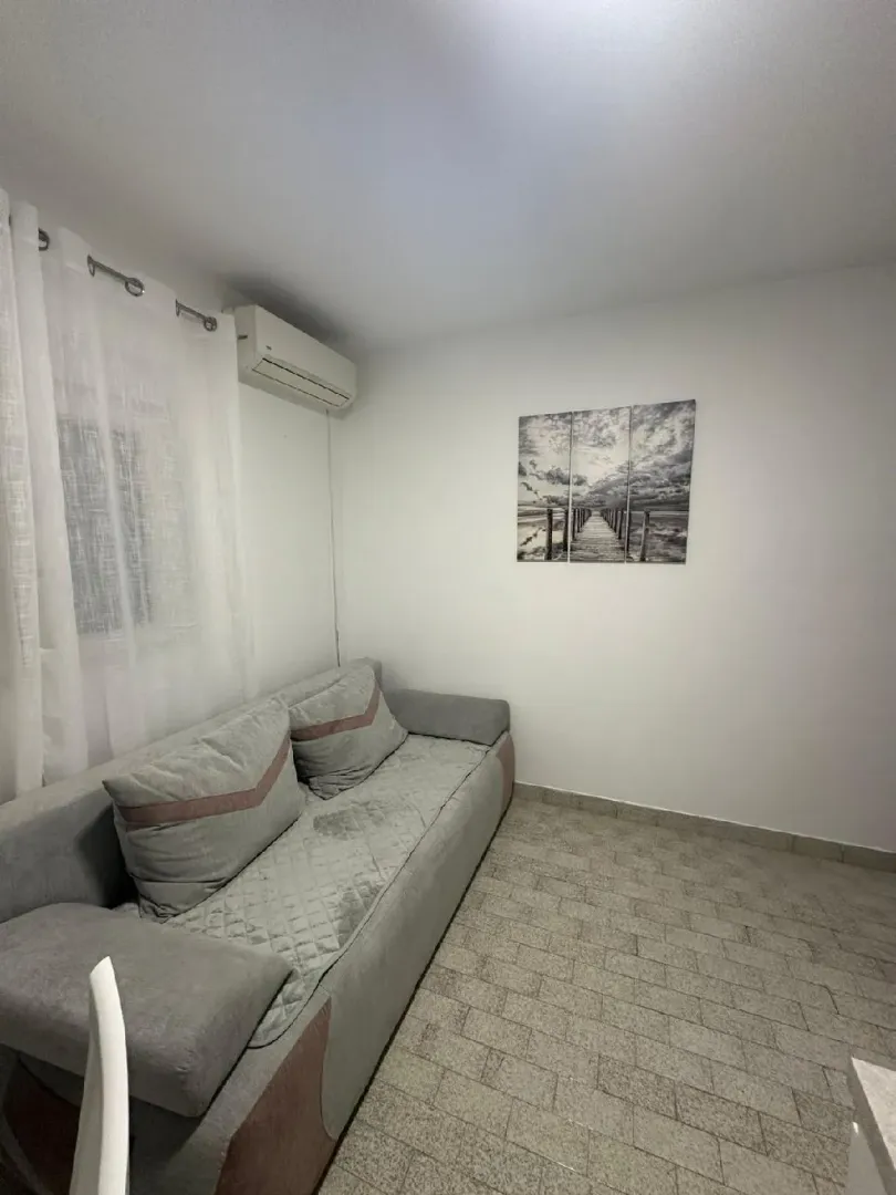 Living room with a grey sofa, air conditioning unit, and wall art.