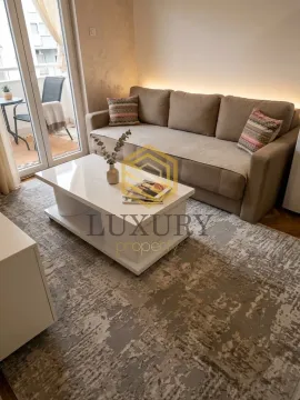 Living room with a sofa, coffee table, and balcony access. - image 6