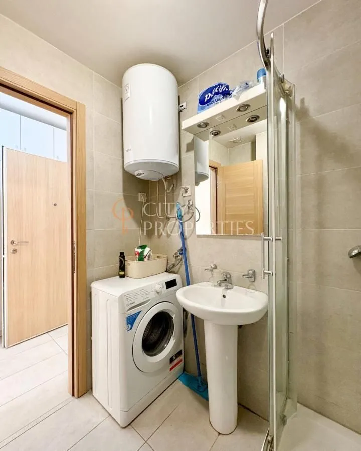 Bathroom equipped with a washbasin, washing machine, shower cabin, and water heater.