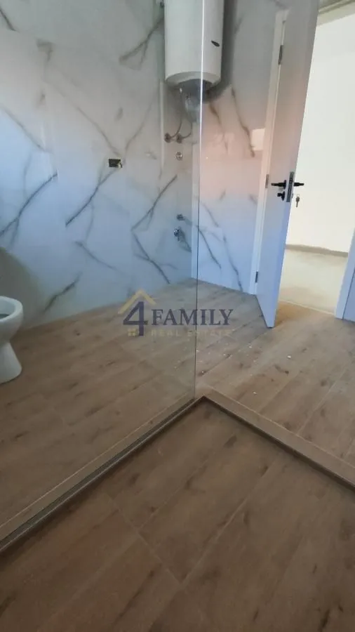 Pogled na moderno uređeno kupatilo sa tuš kabinom i keramičkim pločicama.