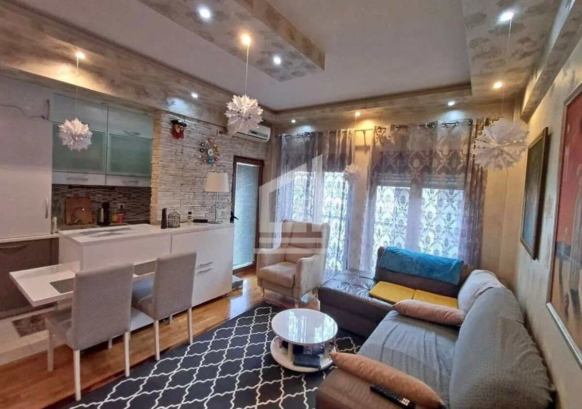 Living room with a sofa, dining area, and kitchen in the background.