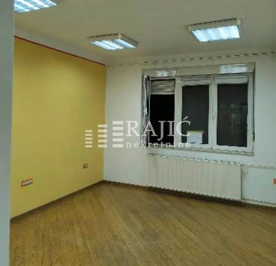 Empty room with hardwood floors, a yellow wall, and a window.