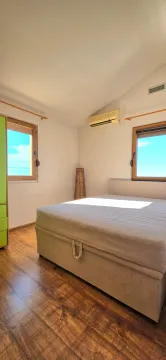 Bright bedroom with a double bed, wooden floor, and two windows. - image 11