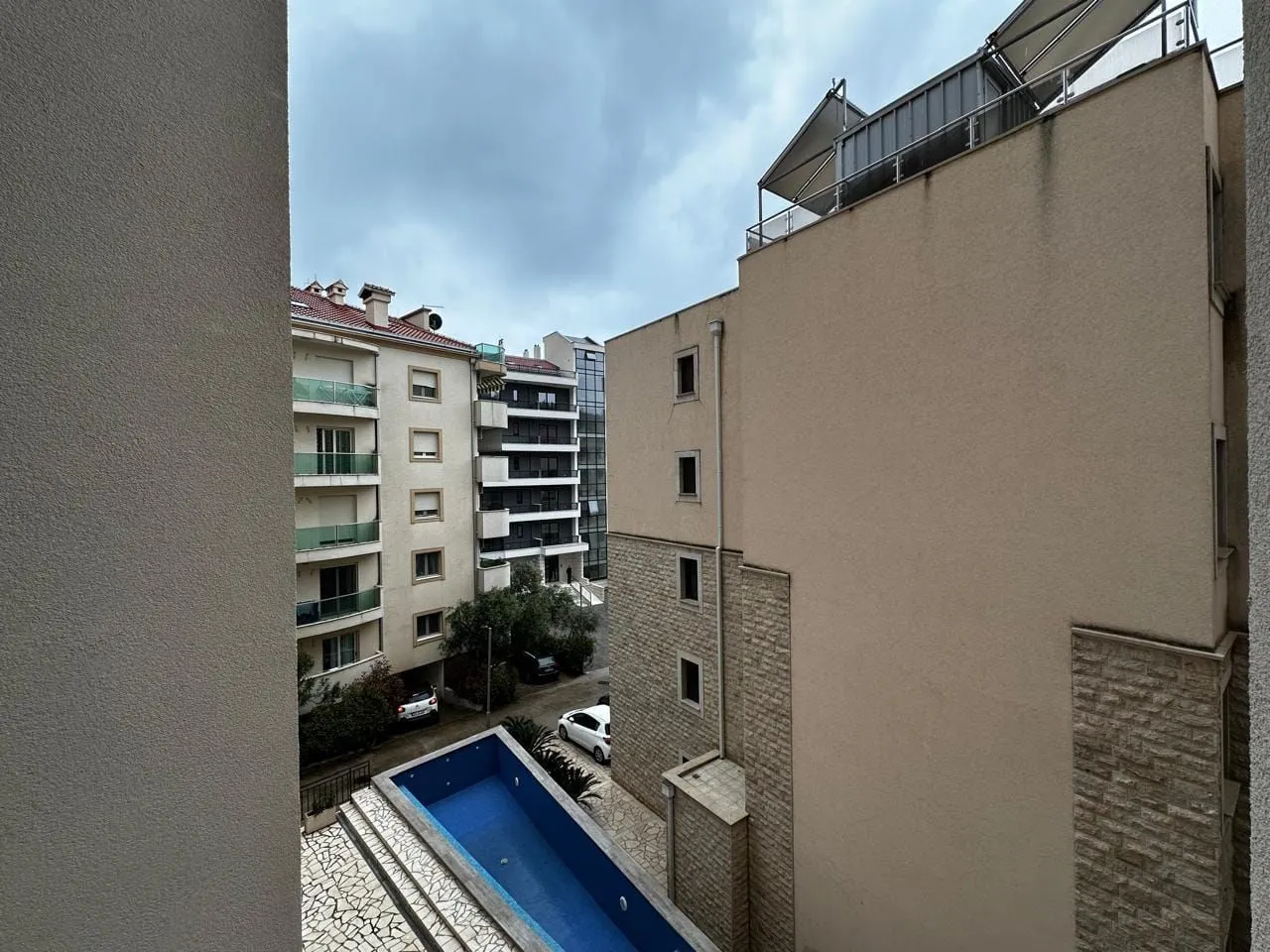 View from the window overlooking surrounding buildings and an outdoor pool.