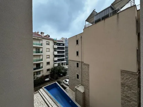 View from the window overlooking surrounding buildings and an outdoor pool. - image 9