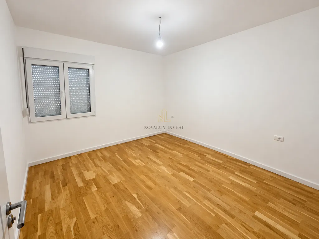 Empty room with white walls and wooden flooring.