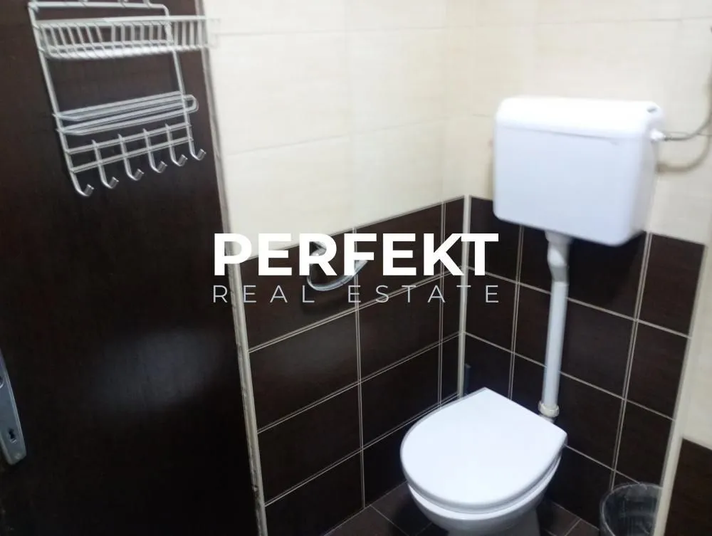 Pogled na kupatilo sa WC šoljom i zidnim pločicama.