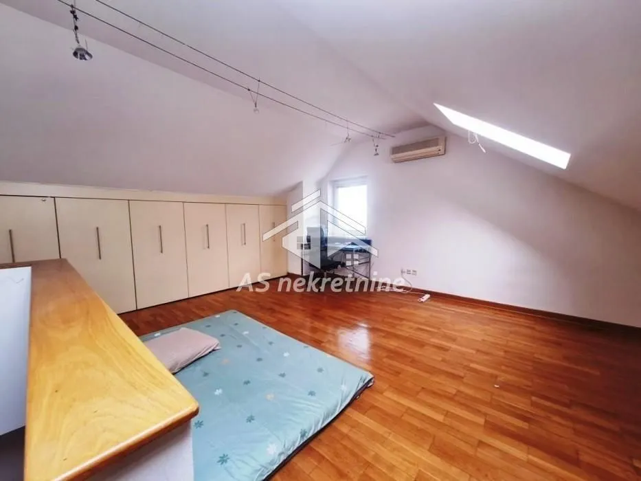 Attic room furnished as a bedroom with built-in wardrobes and hardwood floors.