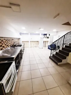 Spacious kitchen with stainless steel workstations and a staircase. - image 8
