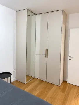 Spavaća soba sa velikim ugradnim garderoberom sa ogledalom i drvenim podom. - image 4