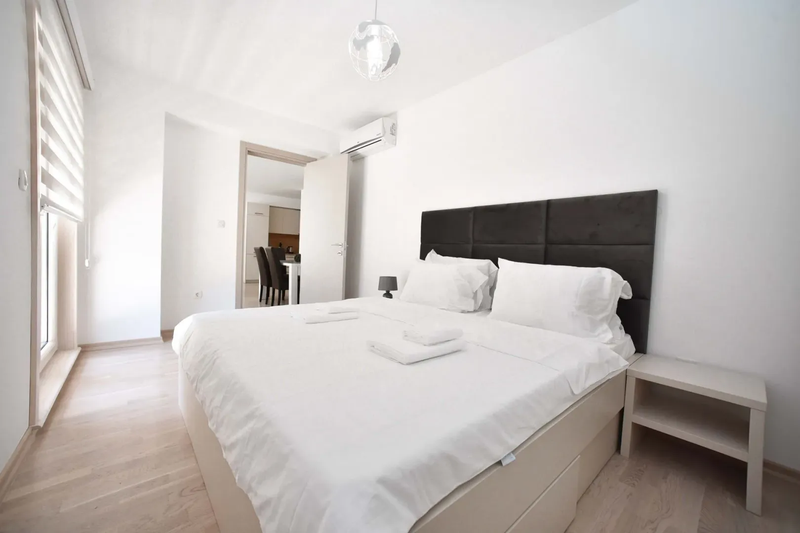 Bright bedroom with a large double bed and a view into the interior of the apartment.