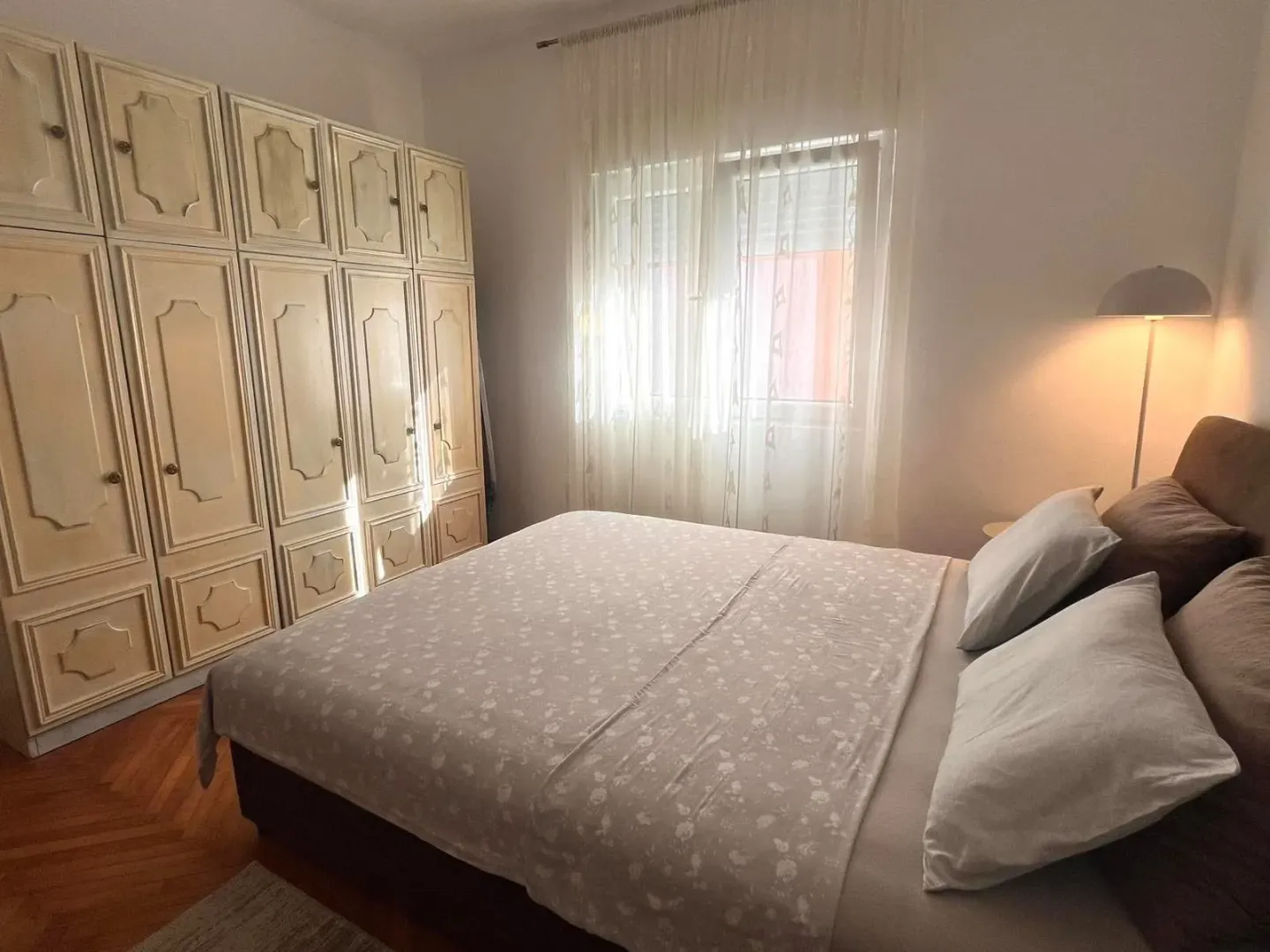 Spavaća soba sa velikim bračnim krevetom, garderoberom i prozorom.