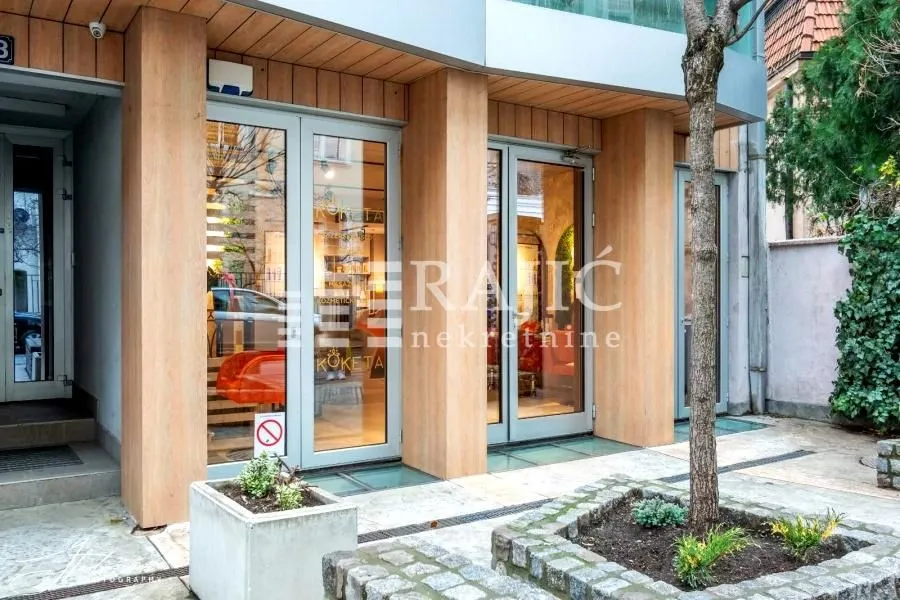 Exterior of a commercial space with glass entrance doors and wooden pillars.