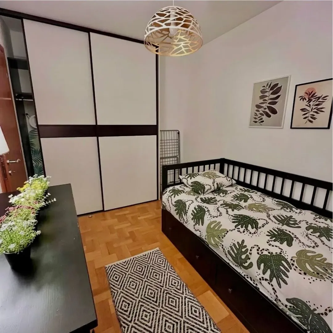 Small bedroom with a bed, built-in wardrobe, and parquet flooring.