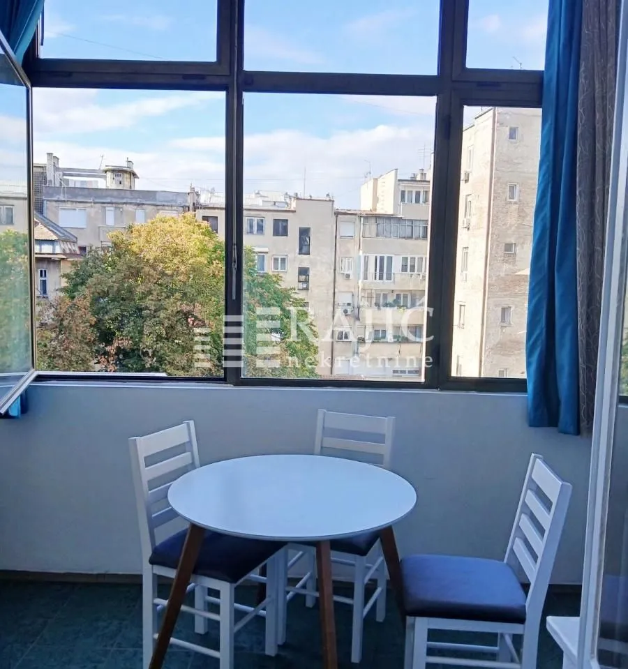 Enclosed balcony with a dining table and city view.