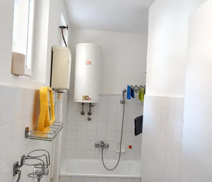 Bathroom with a bathtub, water heater, and white wall tiles. - image 4