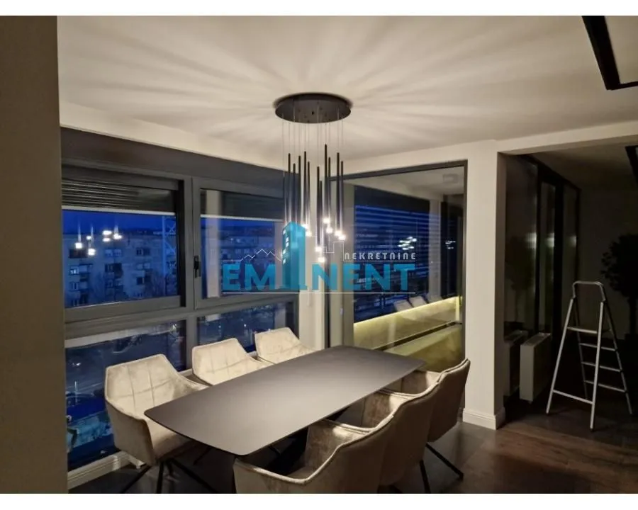 Dining area with a modern table, chairs, and chandelier.
