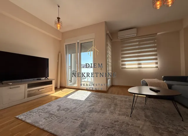 Spacious living room with a sofa, large TV, and access to the terrace.