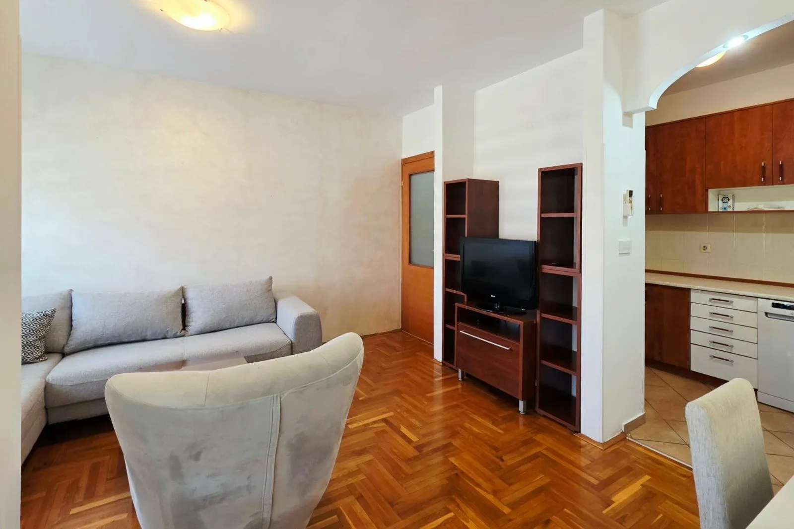 Living room with a sofa, TV unit, and view of the kitchen.