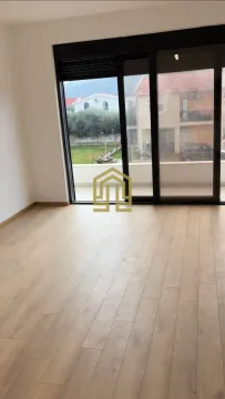 Prazna svijetla prostorija sa drvenim podom i velikim staklenim vratima koja vode na terasu. - image 4