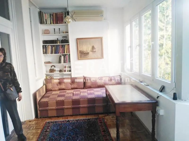 Living room with a sofa, bookshelf, and large windows.